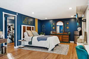 Bedroom with a walk in closet, wood-type flooring, stainless steel refrigerator, and a closet