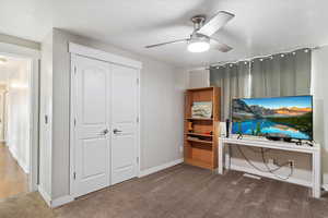 Carpeted bedroom featuring ceiling fan, a textured ceiling, and a closet