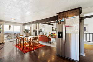 Dining space featuring beam ceiling, dark wood-type flooring, and a textured ceiling