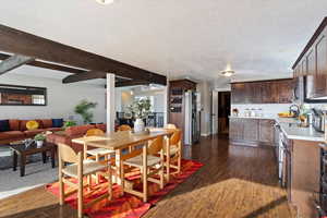 Dining room featuring beam ceiling, a textured ceiling, dark wood-type flooring, and sink