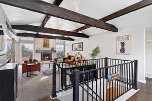 Interior space featuring a textured ceiling, vaulted ceiling with beams, and dark wood-type flooring