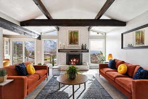 Living room with vaulted ceiling with beams, a textured ceiling, a wealth of natural light, and a brick fireplace