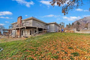 Back of property with a yard and a deck with mountain view