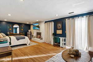 Bedroom featuring hardwood / wood-style floors, a fireplace, and a textured ceiling