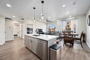 Kitchen featuring pendant lighting, a kitchen island with sink, sink, stainless steel dishwasher, and ceiling fan