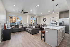 Kitchen with gray cabinets, a kitchen island with sink, sink, and decorative light fixtures