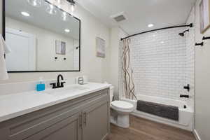 Full bathroom with hardwood / wood-style floors, vanity, toilet, and shower / bathtub combination with curtain