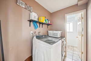 Laundry area featuring light tile patterned floors and washing machine and clothes dryer