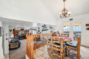 Dining room featuring lofted ceiling, light tile patterned floors, and an inviting chandelier