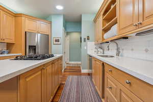 Kitchen with dark hardwood / wood-style flooring, sink, decorative backsplash, and stainless steel appliances