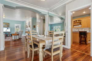 Dining space featuring dark hardwood / wood-style floors, ornate columns, ornamental molding, and sink