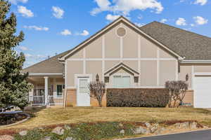 View of front of home featuring covered porch, a garage, and a front lawn