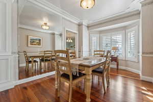 Dining area with hardwood / wood-style floors, a notable chandelier, and ornamental molding