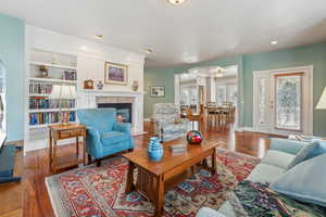 Living room featuring built in shelves, wood-type flooring, and a fireplace