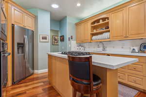 Kitchen with stainless steel appliances, tasteful backsplash, light hardwood / wood-style floors, a breakfast bar area, and a kitchen island