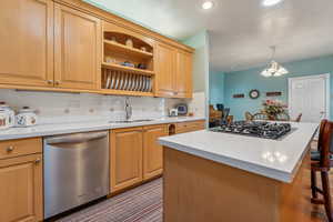 Kitchen featuring decorative backsplash, appliances with stainless steel finishes, a breakfast bar, sink, and decorative light fixtures