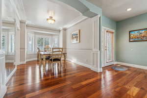 Dining space with ornamental molding and dark wood-type flooring