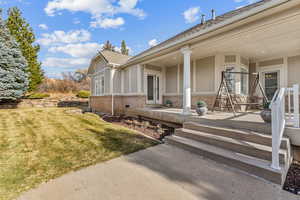 View of exterior entry with a lawn and covered porch