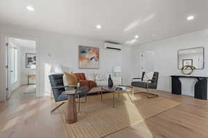 Living room featuring light hardwood / wood-style floors and a wall unit AC