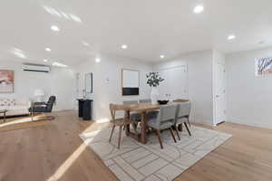 Dining room with light hardwood / white oak floors and a wall mounted AC