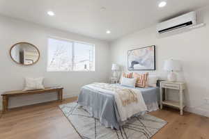 Bedroom with light hardwood / wood-style flooring and a wall mounted air conditioner