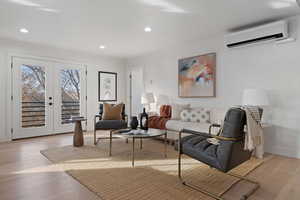 Living room featuring french doors, a wall unit AC, and light hardwood / wood-style flooring