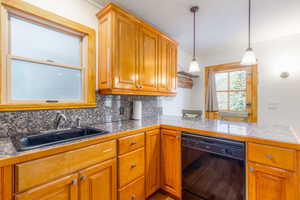 Kitchen featuring kitchen peninsula, tasteful backsplash, sink, dishwasher, and hanging light fixtures