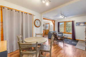 Dining space with wood-type flooring, crown molding, and track lighting