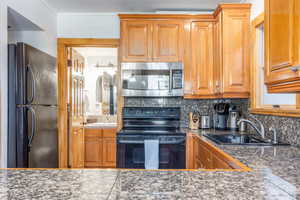 Kitchen featuring decorative backsplash, sink, and black appliances