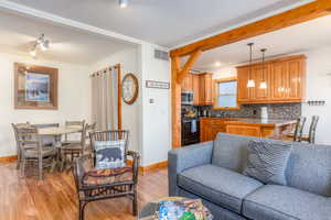 Living room featuring light wood-type flooring, ornamental molding, and track lighting