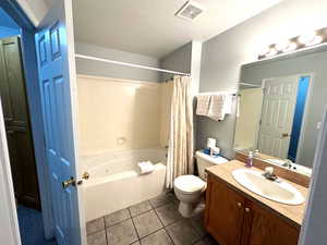 Full bathroom featuring tile patterned floors, shower / bath combination with curtain, a textured ceiling, toilet, and vanity