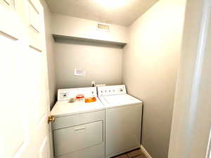 Washroom featuring independent washer and dryer, a textured ceiling, and tile patterned floors