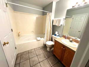 Full bathroom featuring vanity, tile patterned flooring, toilet, a textured ceiling, and shower / tub combo with curtain