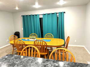 Dining space featuring a textured ceiling and carpet floors