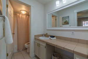 Bathroom with vanity, tile patterned flooring, ceiling fan, toilet, and walk in shower