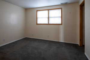 Spare room with dark colored carpet