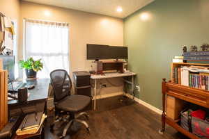 Office space featuring a wealth of natural light, dark wood-type flooring, and a textured ceiling