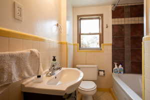 Full bathroom with sink, toilet, and tile walls