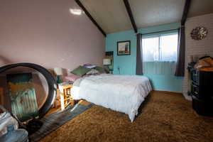 Carpeted bedroom featuring lofted ceiling with beams