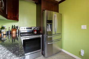 Kitchen with appliances with stainless steel finishes and dark stone counters