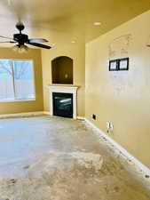 Unfurnished living room featuring ceiling fan, concrete flooring, and a textured ceiling