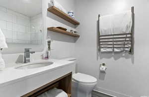 Bathroom with hardwood / wood-style flooring, vanity, and toilet