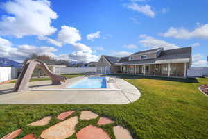 View of swimming pool with a lawn, a patio, and a water slide