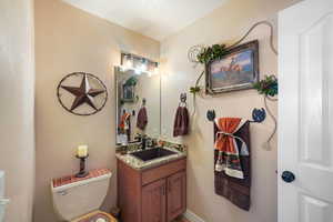 Bathroom with a textured ceiling, vanity, and toilet