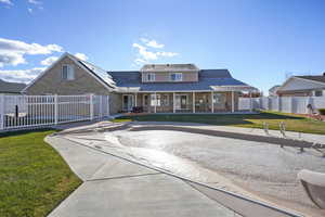 View of front facade featuring covered porch, solar panels, and a front yard