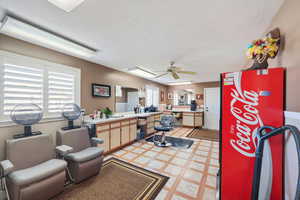 Interior space with a textured ceiling, ceiling fan, and a healthy amount of sunlight