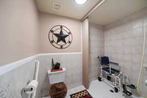 Bathroom featuring tile patterned floors and tile walls