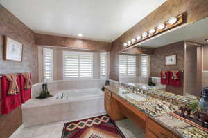 Bathroom with tile patterned flooring, vanity, and tiled bath