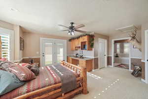 Bedroom with ceiling fan, light colored carpet, a textured ceiling, and multiple windows