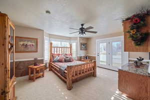 Bedroom featuring access to outside, ceiling fan, light colored carpet, and a textured ceiling